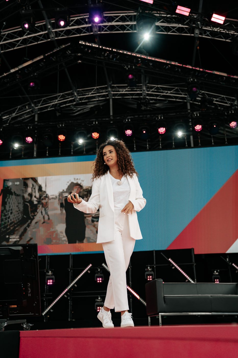 Domitila palestrando num grande palco, de terno branco