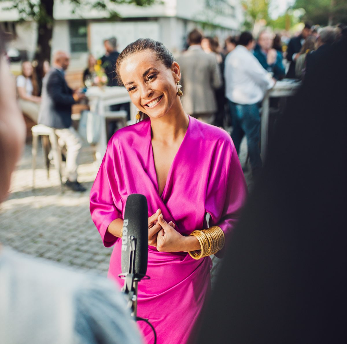 Domitila de vestido rosa dando entrevista diante de um microfone