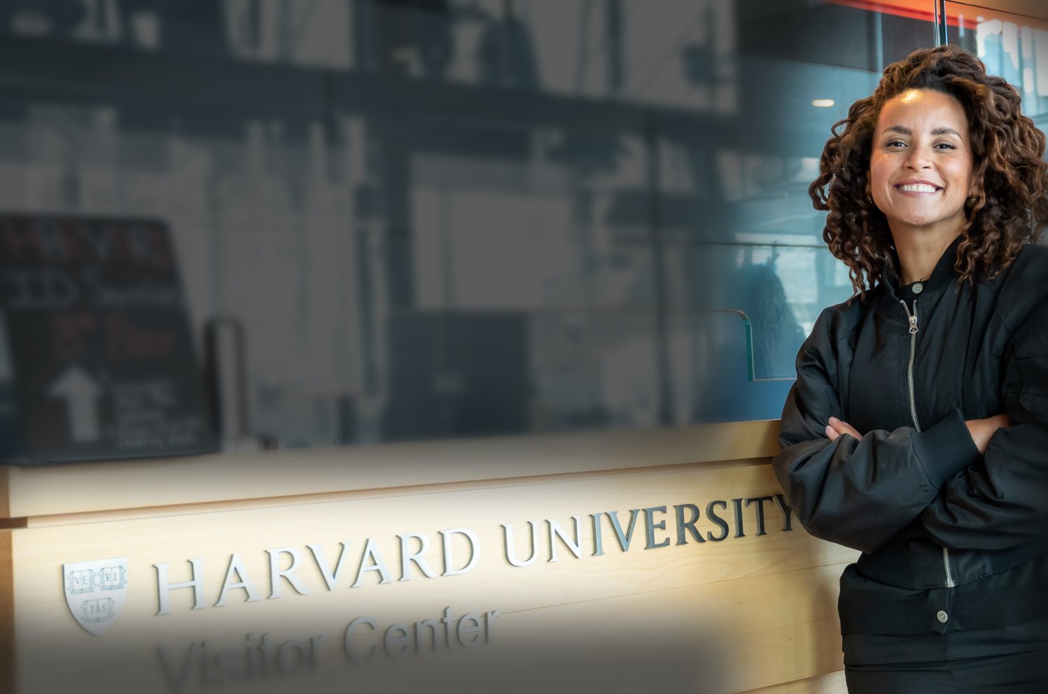 Domitila sorrindo ao lado do letreiro Harvard University