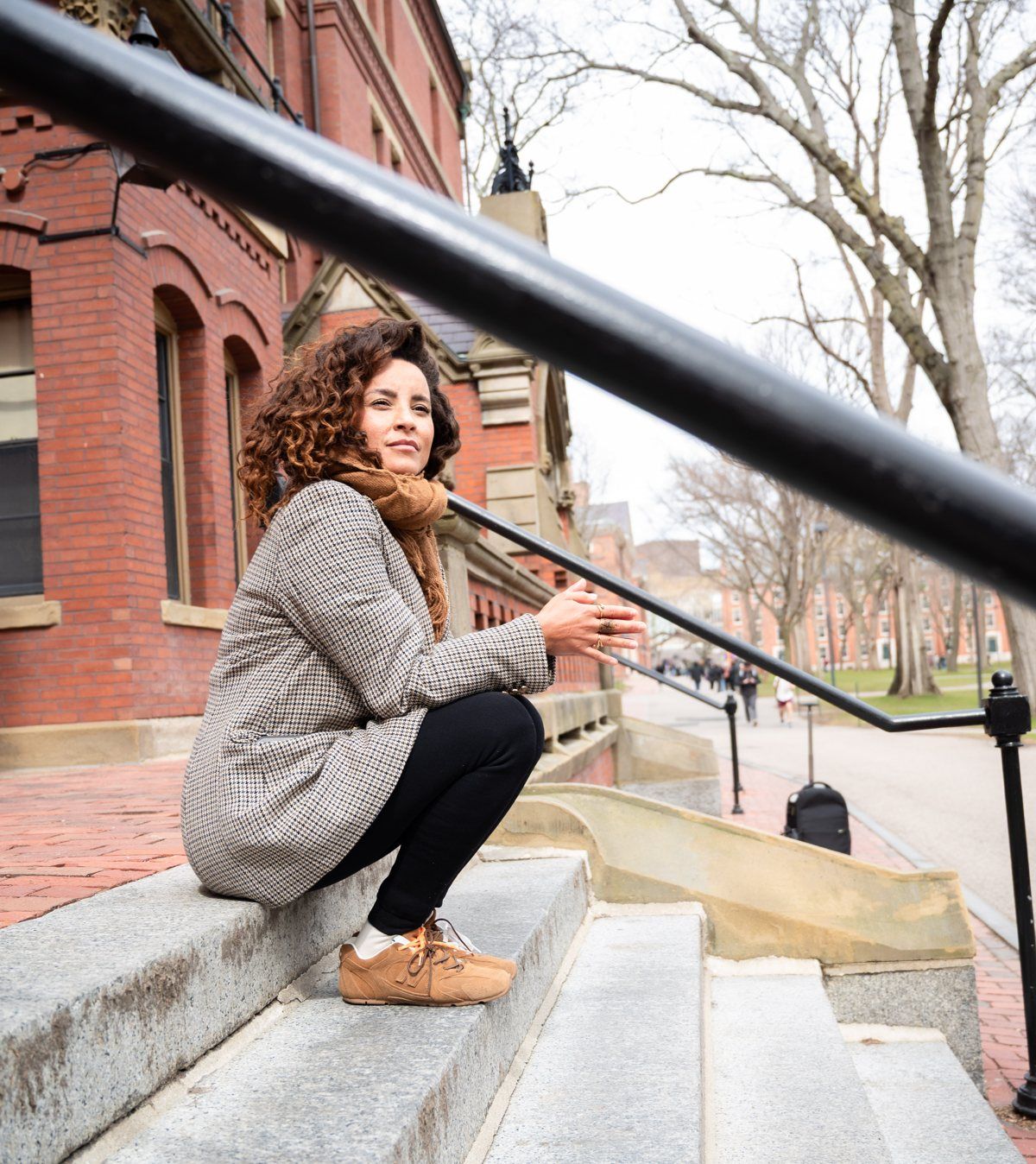 Domitila sentada na escadaria de um prédio de tijolos em Harvard